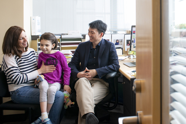 The Vital Science podcast episode 02 is an image of Mila sitting on Julia's lap, meeting with Dr. Yu in his office.