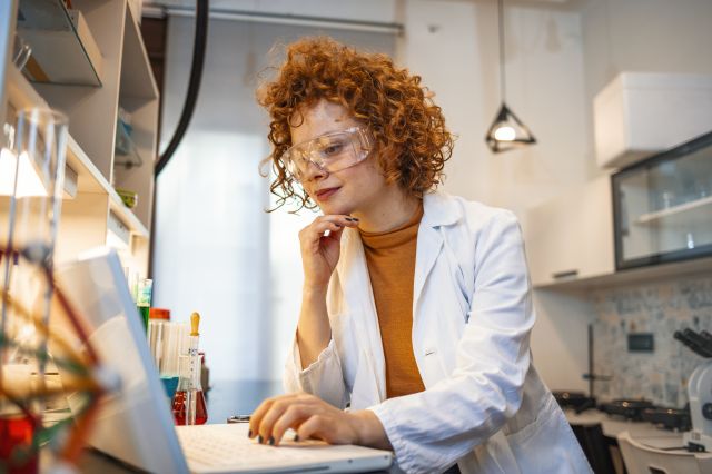 female scientist in lab coat working on laptop