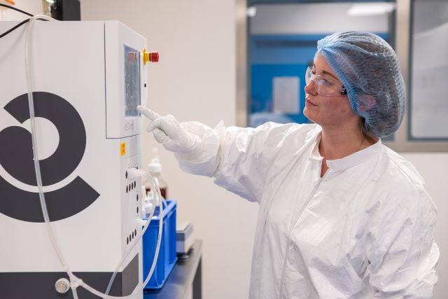 Scientist in a lab wearing PPE using a device for Plasmid DNA Research.