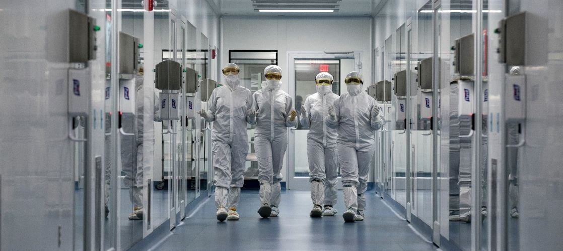 Scientists wearing full PPE walking down a hall at the Memphis facility.
