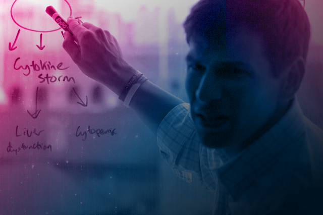 Headshot of Dr. David Fajgenbaum pointing to scientific information on a whiteboard.