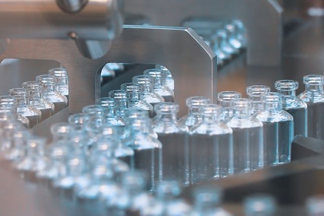 vaccine bottles on an assembly line