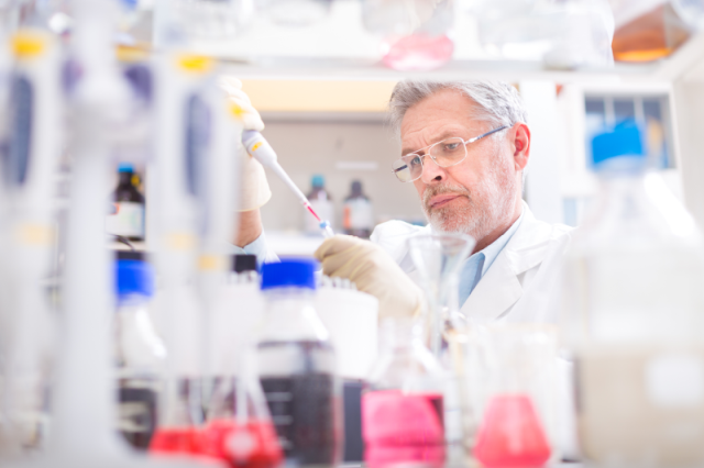 Charles River scientist working in a lab, pipetting into a test tube.