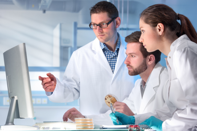 scientists working on microbial identification and looking ata flatscreen monitor
