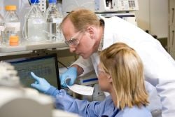 Scientists in a lab, looking at computer screen.