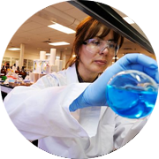 Scientist pouring blue liquid from a flask.