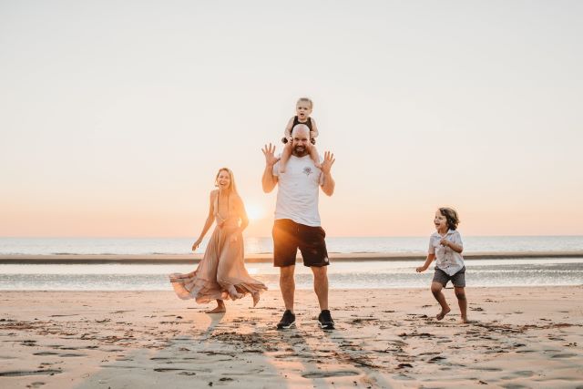 Whitrod family playing on a beach at sunset.