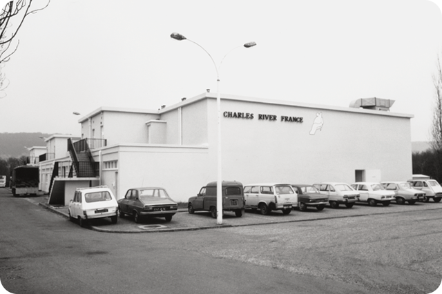 Historic Charles River France facility with parked cars in front, showcasing the company’s early international presence in biomedical research
