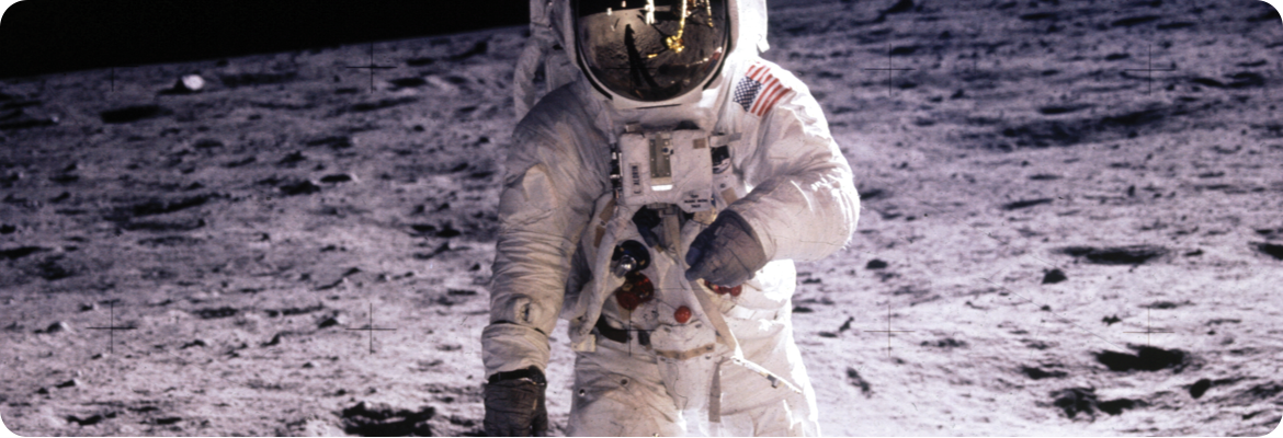 Astronaut in a spacesuit standing on the lunar surface, with the moon's barren terrain visible in the background