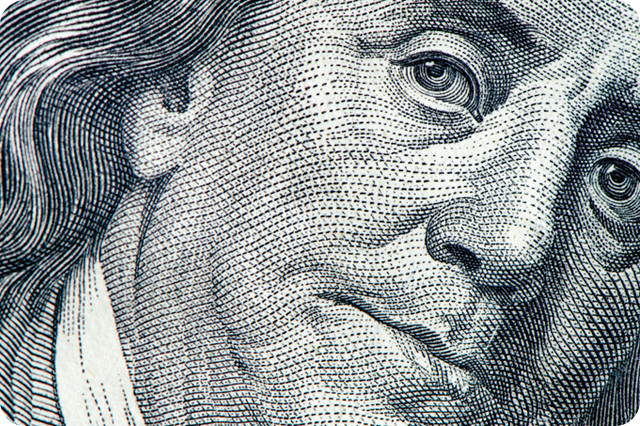 Extreme close-up of the portrait of Benjamin Franklin on a US one hundred dollar bill, showing the intricate detail of the engraving.