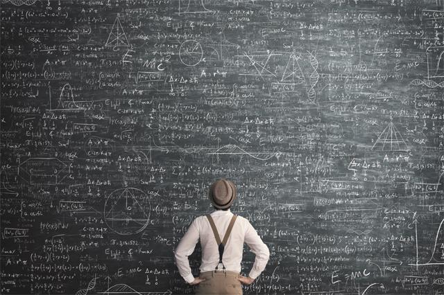 Person examining scientific formulas on chaulkboard