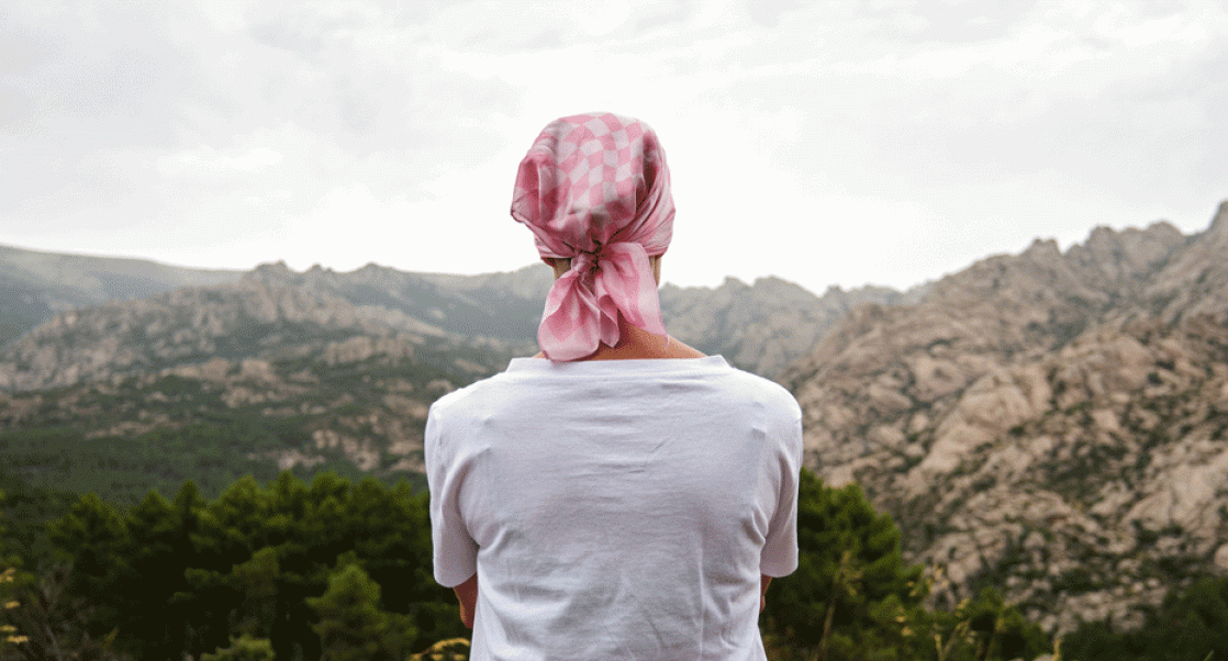 Cancer Survivor looking off into a mountain scene.