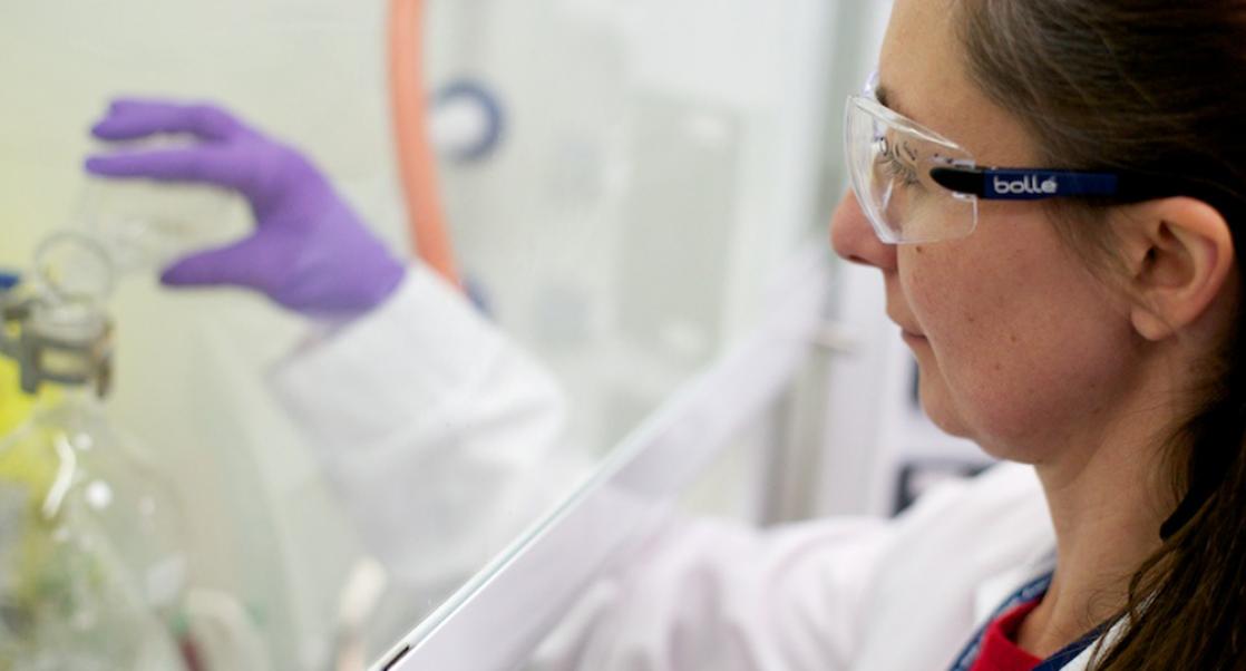 drug discovery scientist pouring liquid from a flask