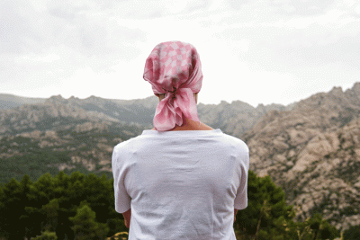 Cancer Survivor looking off into a mountain scene.