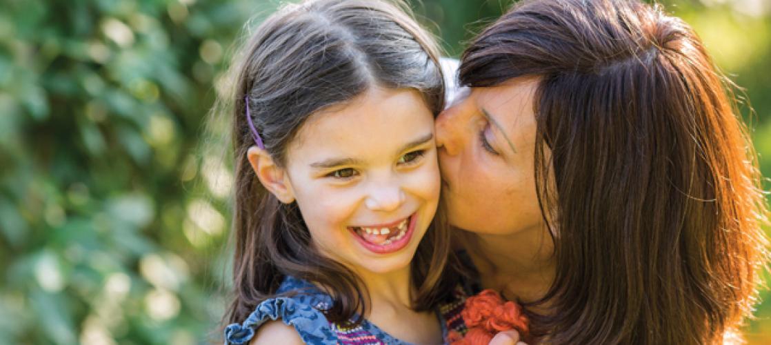 Julia Vitarello kissing her daughter Mila on the cheek, as both smile.