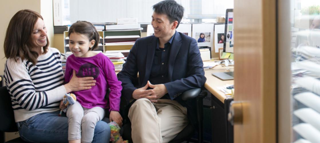The Vital Science podcast episode 02 is an image of Mila sitting on Julia's lap, meeting with Dr. Yu in his office