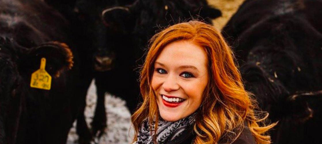 Photo of a smiling Jaci with a herd of angus cows